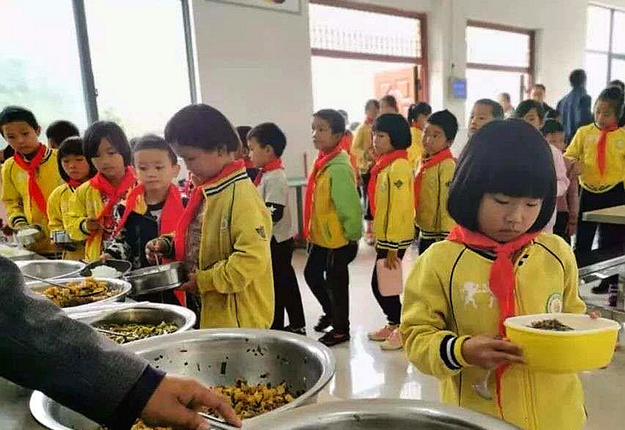 关岭纳磨村纳卜小学学生在食堂排队打饭.jpg