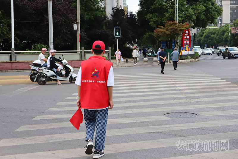 8月5日，黄果树大街大润发段，西秀区凤凰社区服务中心志愿者带领路人过斑马线。