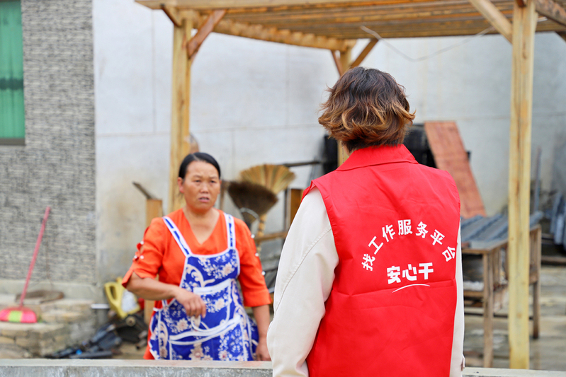 花江镇永睦村村文书张秀英身着定制的红马甲与群众推介“安心干”平台.JPG