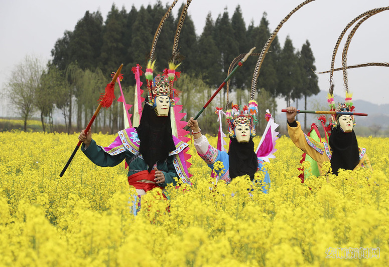 3月17日，地戏表演队员在贵州省安顺市西秀区狗场屯村的油菜花地为游客展示地戏服饰和面具。