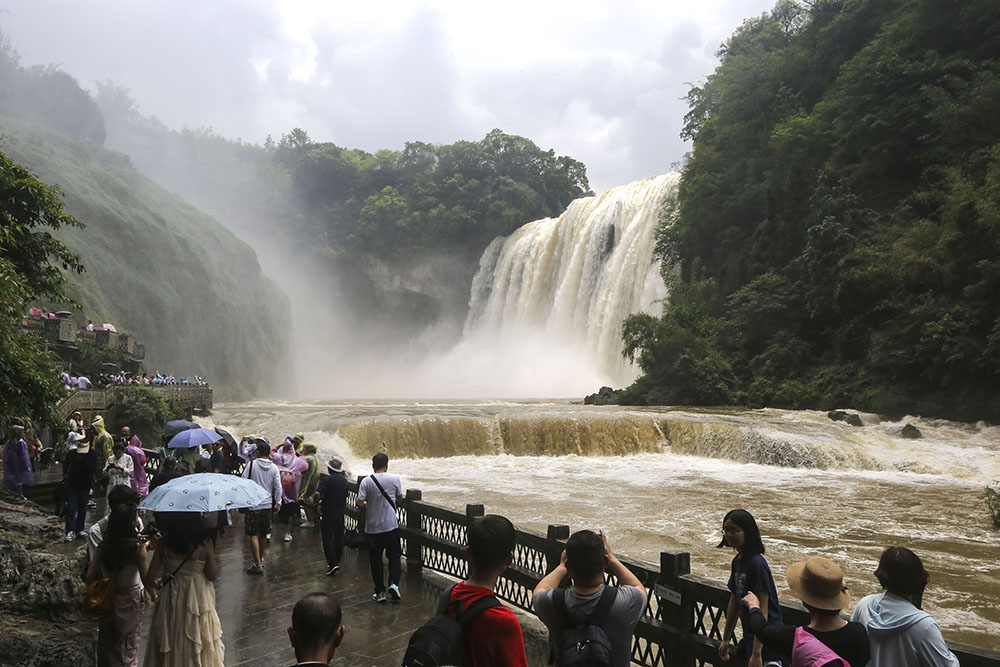 　　近日，受强降雨影响，黄果树瀑布进入丰水期，瀑布飞流直下,气势磅礴，壮观的瀑布吸引游客前来观赏。图为6月20日，游客在安顺黄果树瀑布前观赏。（安顺日报融媒体中心记者 卢维）